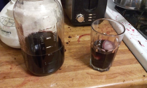 Several glass containers with dark purple serviceberry juice