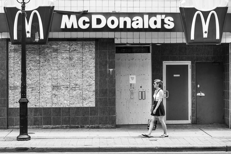 A woman walks past a McDonalds boarded up for G20 in 2010