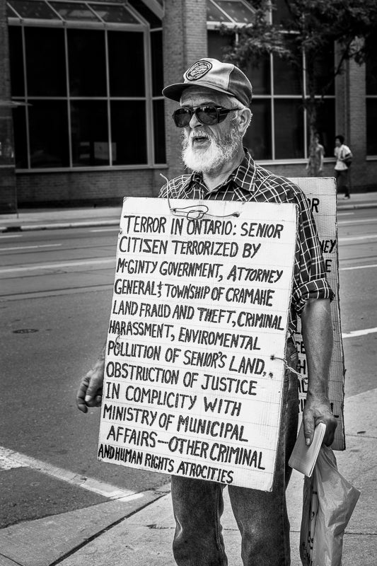 Front side of an old man protesting on streets of Toronto