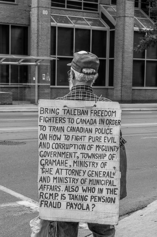 Back side of an old man protesting on streets of Toronto