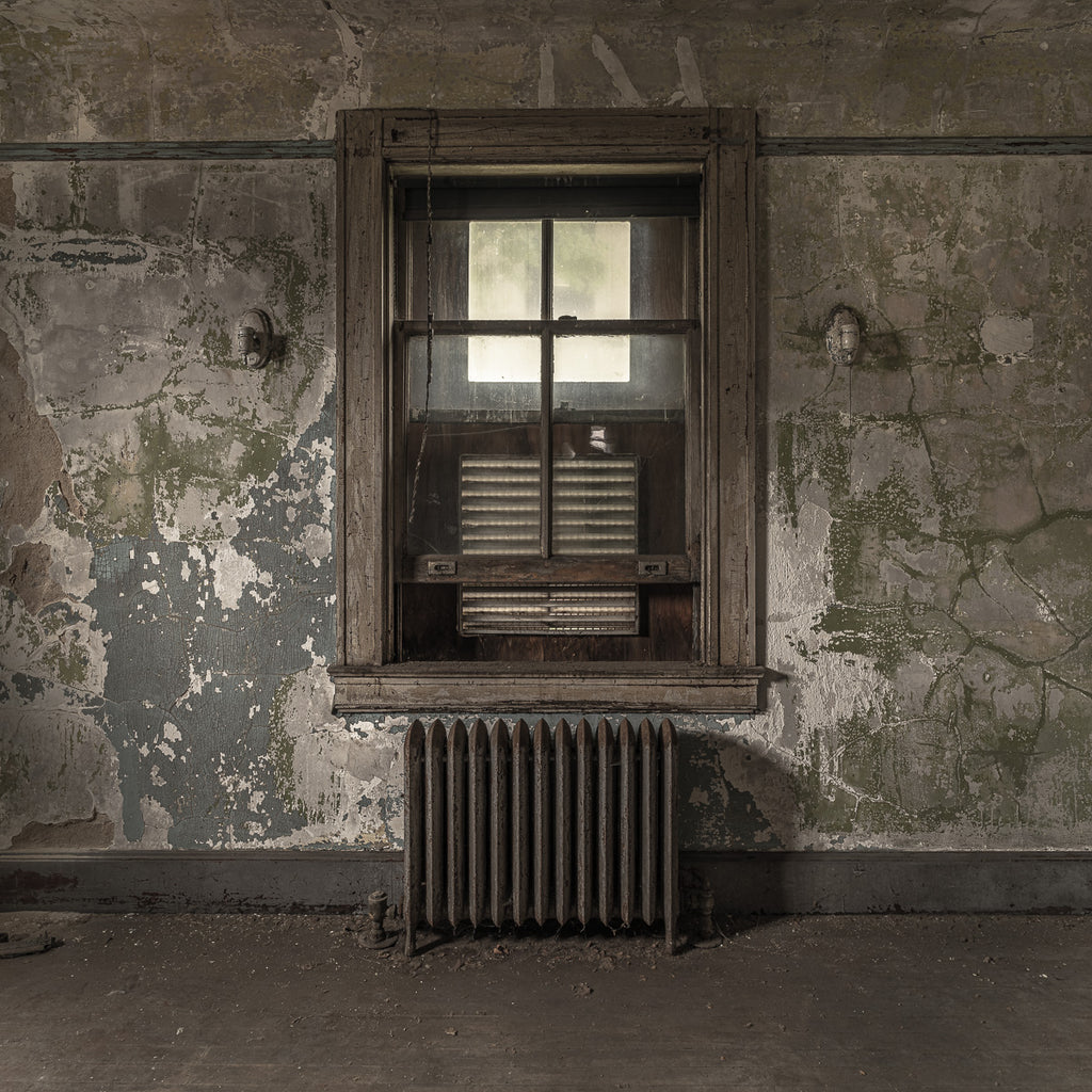 ic:The deserted doctor’s office in the abandoned hospital on Ellis Island holds a somber atmosphere, its empty chairs and fading walls echoing the medical histories and untold stories of those who once sought hope and healing within its confines.