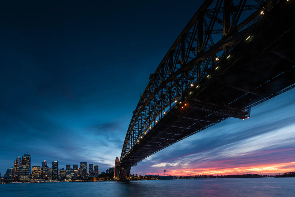 IC: Głębokie błękitne niebo i spokojny most Wrap Sydney w ponadczasowym blasku.