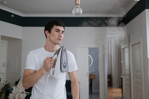 Man in white tee shirt ironing with steam