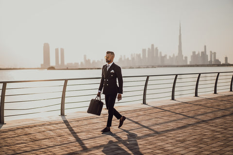 Man in suit holding briefcase walking along waterfront