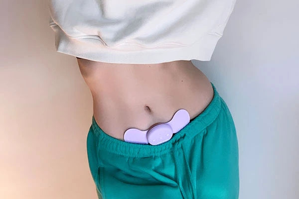 Bridget Hustwaite's stomach with purple Aura TENS machine placed on lower abdominals