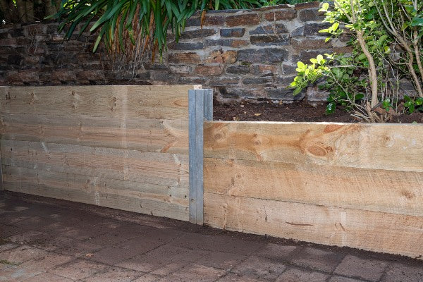 a fully installed sleeper retaining wall with a steel post