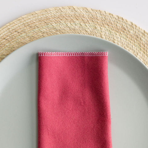 Rosa Pastel (mauve / pink) reusable cotton napkin on a dinner plate and palm placemat inspired by Mexican culture.