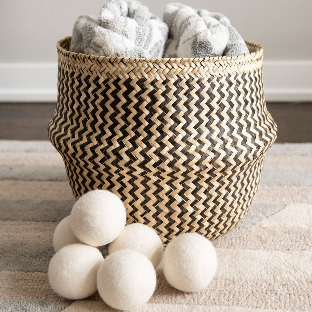 6 large wool dryer balls in front of handwoven belly basket with laundry