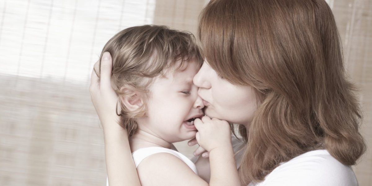 mother kissing crying child