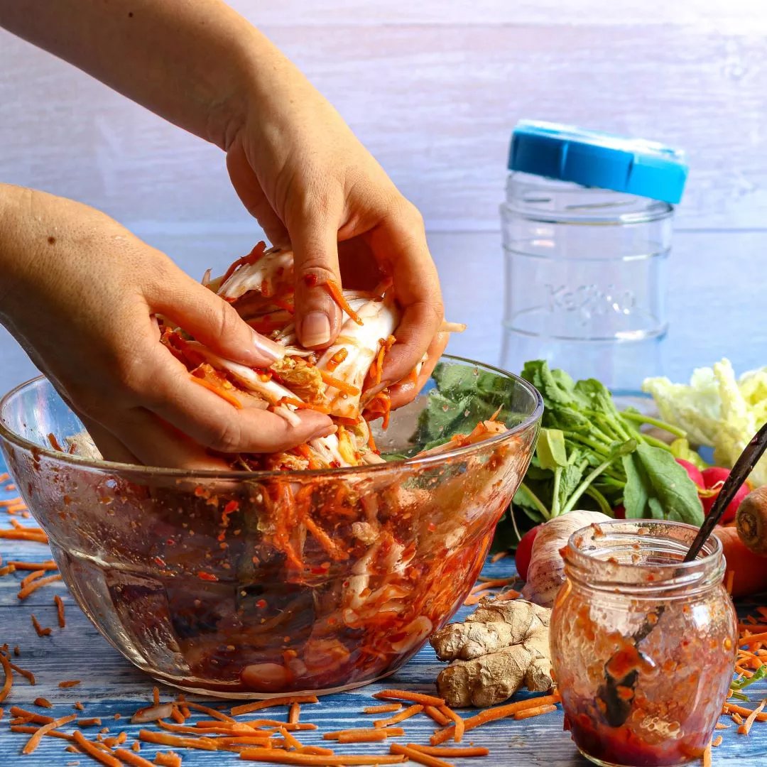 mezclando con las manos los ingredientes para kimchi en un bol de cristal