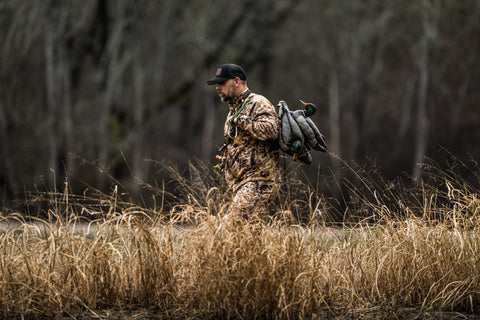 man walking in cat-tails cold weather waterfowl hunting in Kryptek Camo