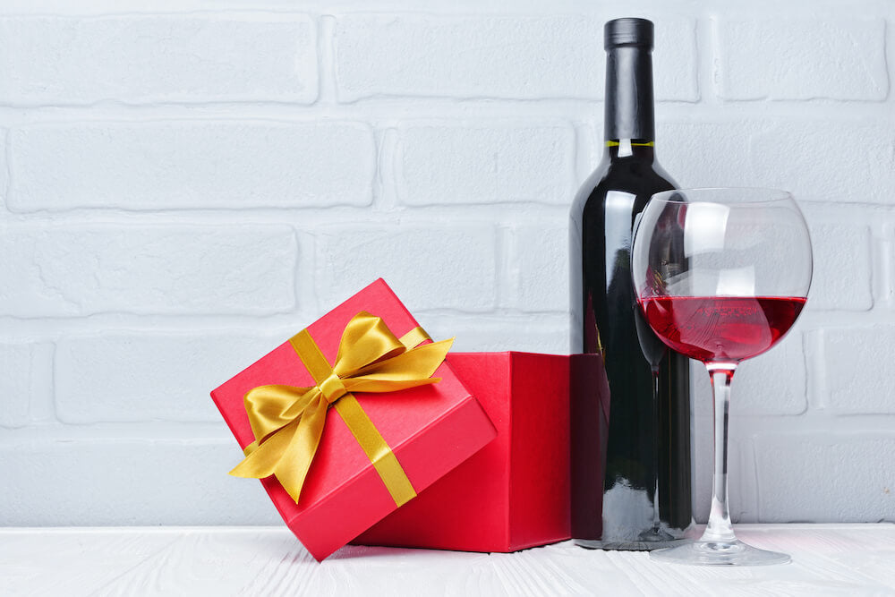 Red wine bottle, glass for tasting and gift box for romantic surprise