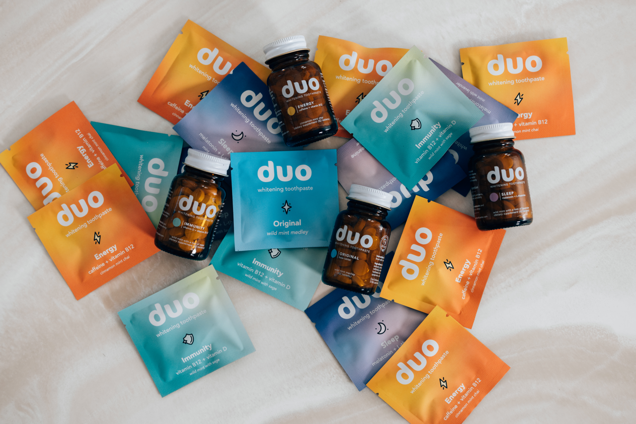 Various colorful packets and bottles of Duo whitening toothpaste and supplements.