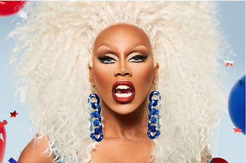 Picture shows a drag queen in blonde hair and dramatic nude makeup with bright blue accessories in a sky background