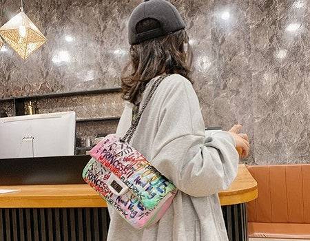 woman slinging a white graffiti bag on her shoulder