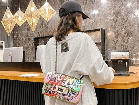 woman wearing a white graffiti bag cross-body style