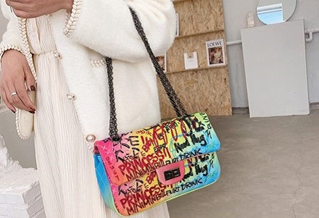 woman slinging a colorful graffiti bag on her arms