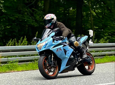 Motorradfahrer auf einer hellblauen Suzuki GSXR1000 L0 mit Knieschleifer vor einer Kurve