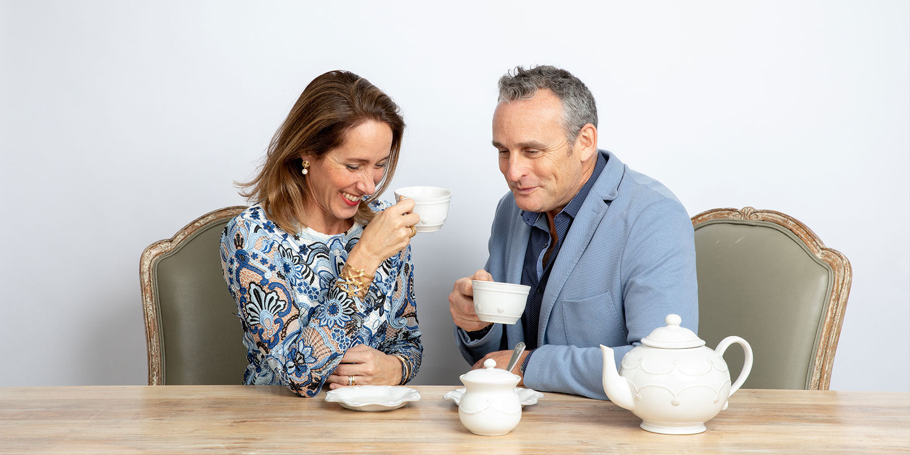 Capucine & David Gooding laugh over a shared cup of coffee.