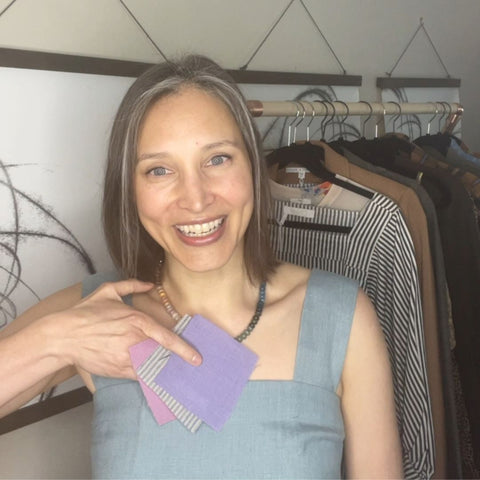 Style for Substance founder Susan Janeczko holding three fabric swatches in front of a rack of clothing.