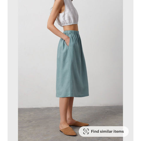Model wearing Etsy store LoveAndConfuse midi skirt in dark turquoise with a white linen top.