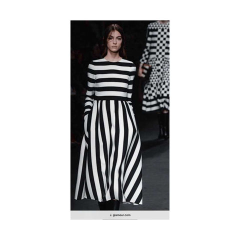 Model in black and white striped dress walking the runway with another model in a black and white dress following her