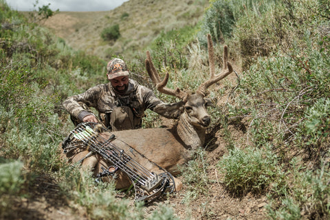 bowhunter with mule deer buck