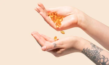A hand dropping oil capsules into another hand