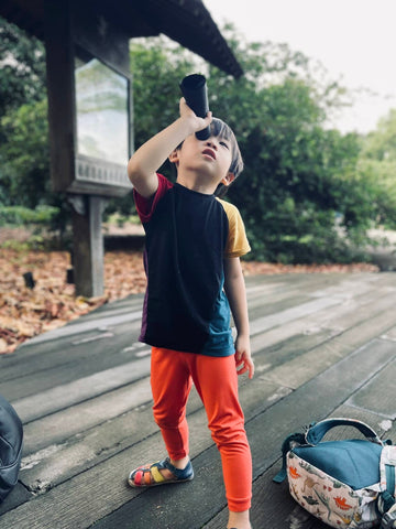 boy wearing orange leggings looking through telescope