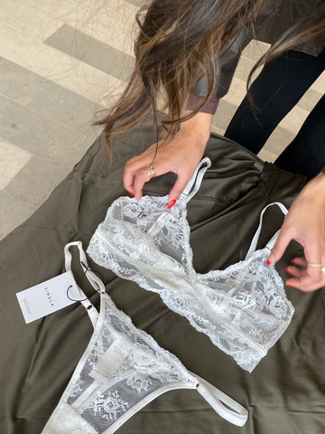 woman's hands fixing white lace lingerie on table