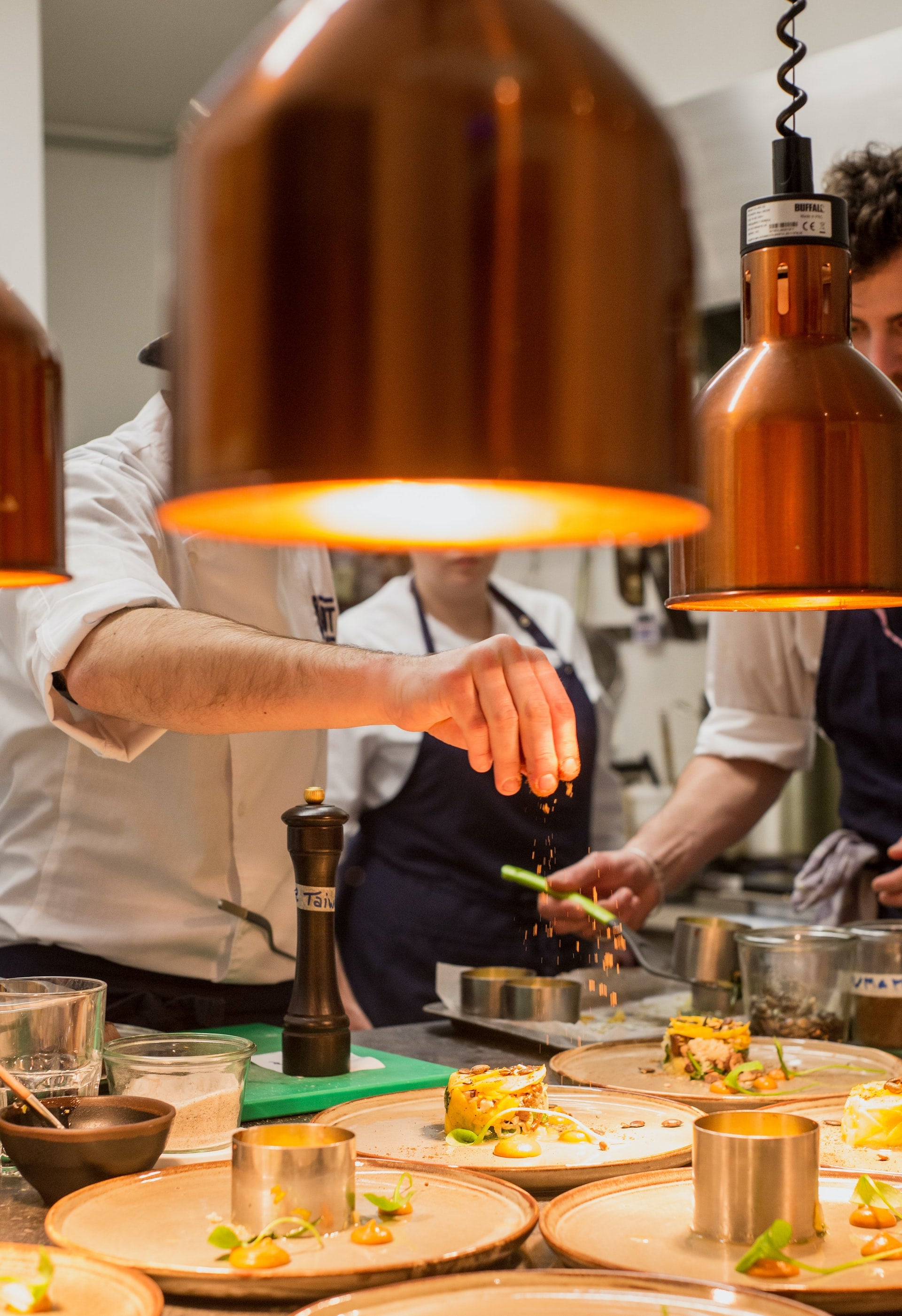 Chefs wearing aprons and preparing dishes in kitchen