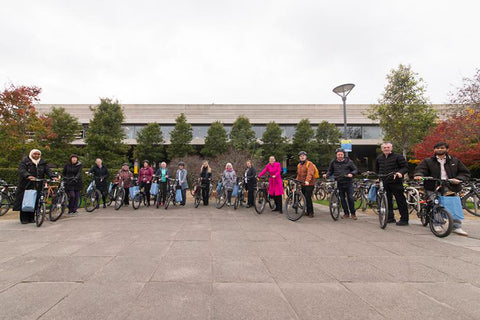 Participants in the UCD Bike Library trial are shown receiving their electric bikes on the university campus.