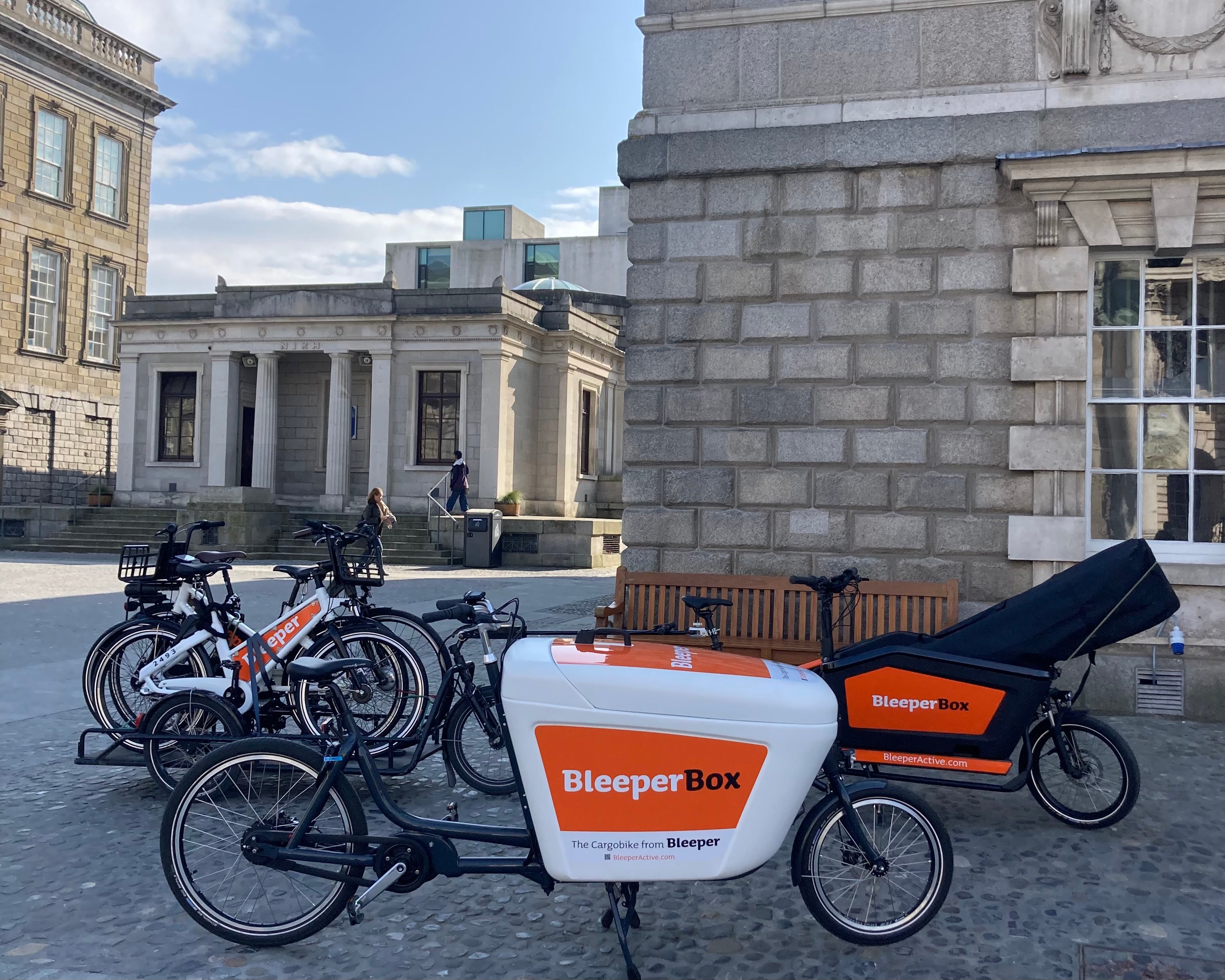 Bleeper public rental bikes on a trailer carried by a Bleeper eCargobike at Trinity College Dublin.