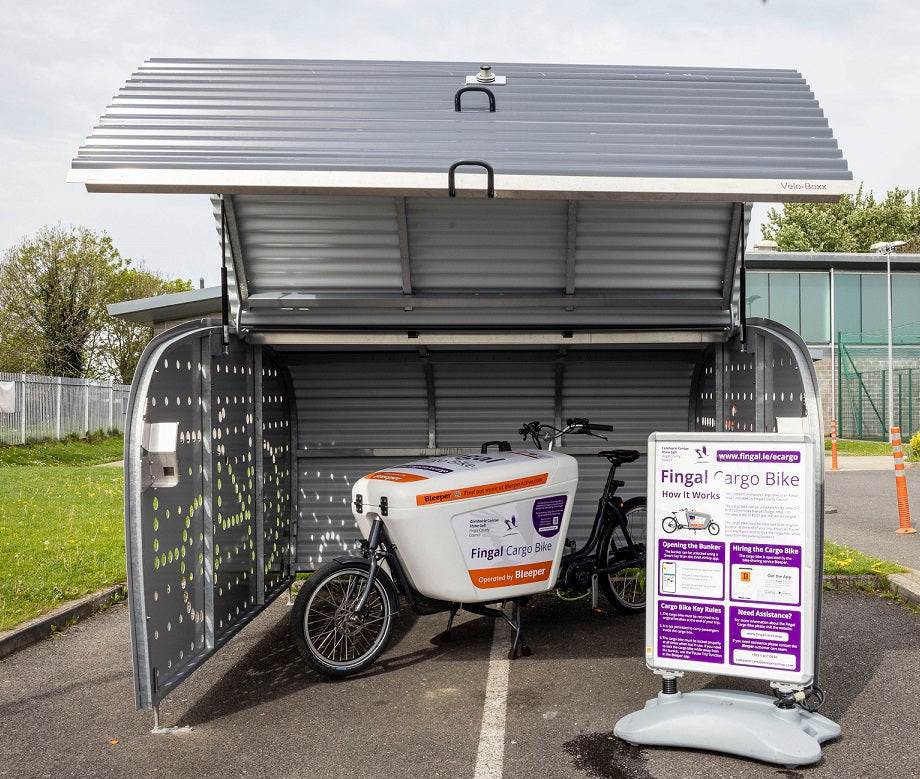 The Fingal Shared Cargo Bike is shown inside its bike bunker. The cargo bike is operated by Bleeper and can be hired using the Bleeper app. The bunker can be accessed using a smartphone with the EVVA app.