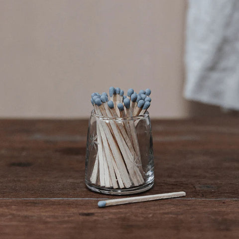 small glass bottle etched with stars filled with grey topped matches