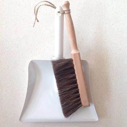 white metal dustpan and a wooden handled brush