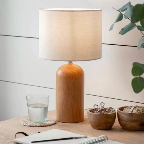 a wooden table lamp lighting up a desk