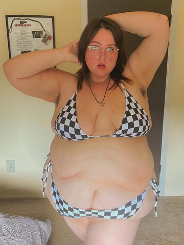 Plus size person with brown hair wearing a checker print string bikini.