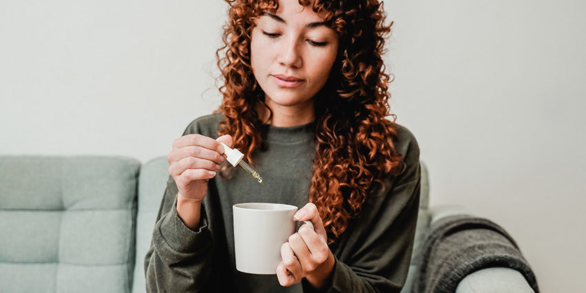 Woman using water soluble CBD oil for anxiety with her tea.