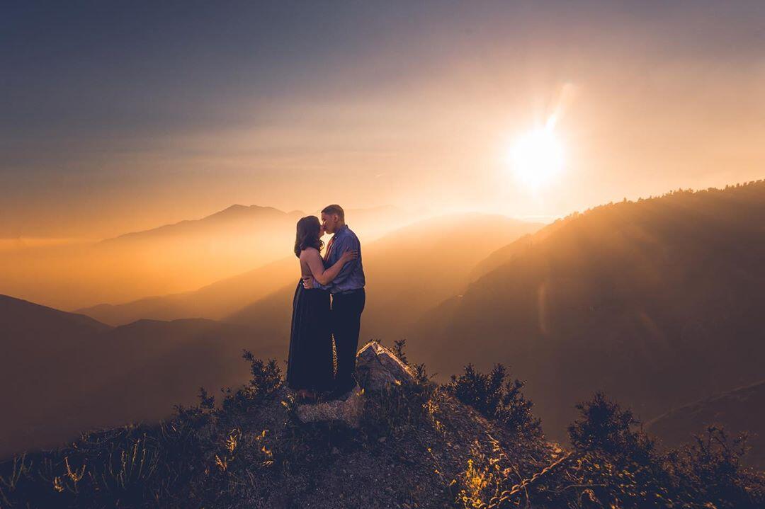 couple on top of a mountain at sunset kissing