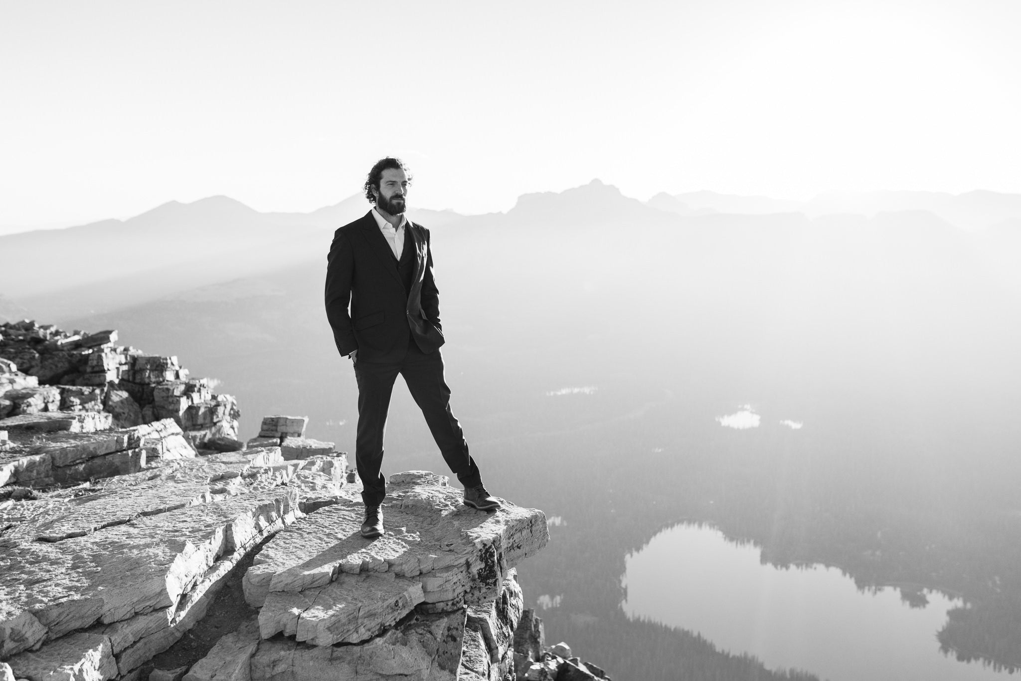 A groom standing on top of a cliff with his hands inside his pockets