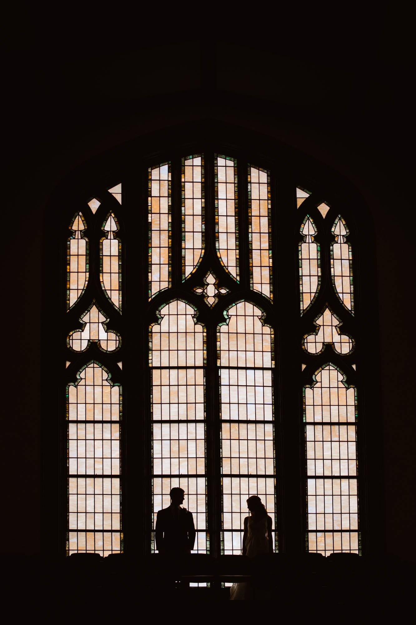 A silhouette of a couple standing in front of a window at the wedding ceremony site