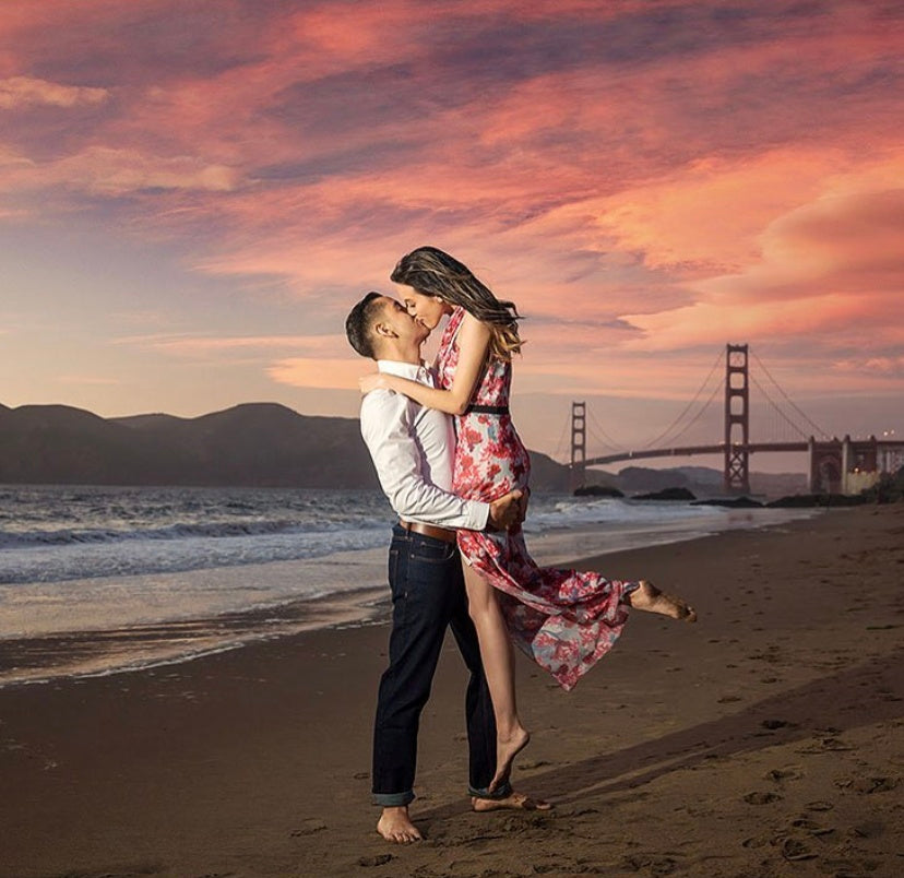 a couple posing for a kiss by the beach during sunset