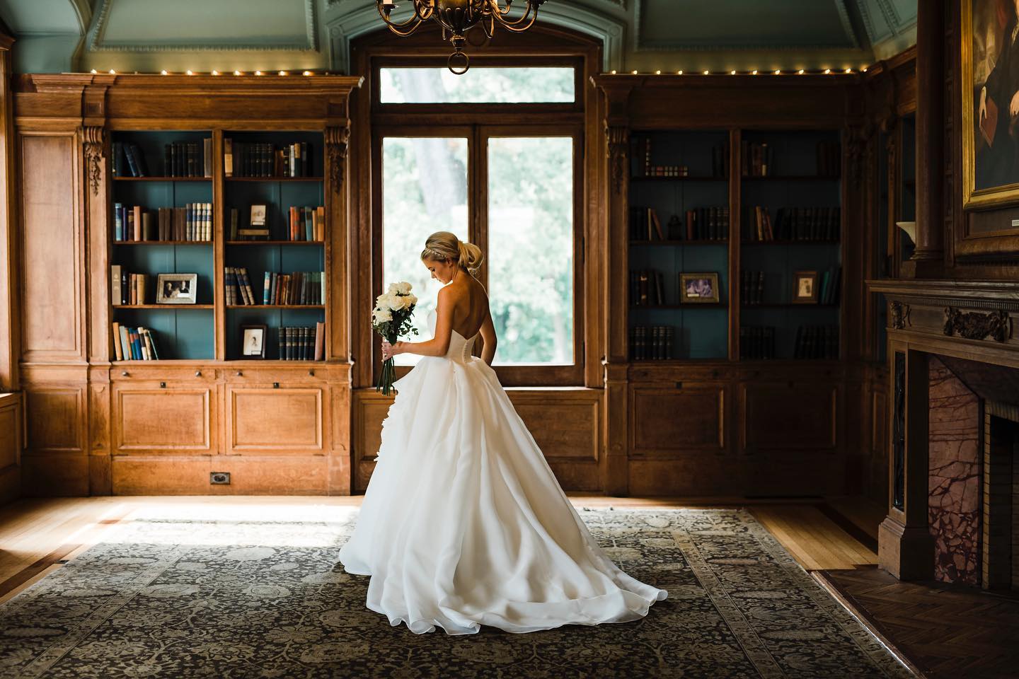 A bride standing in front of a window while holding her bridal bouquet