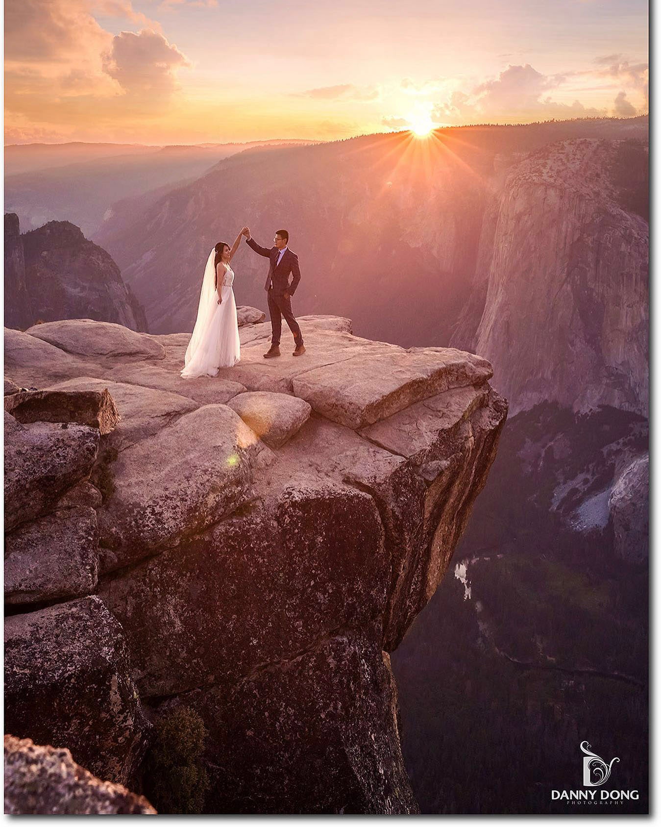 a newlywed couple beside a cliff dancing infront during sunset