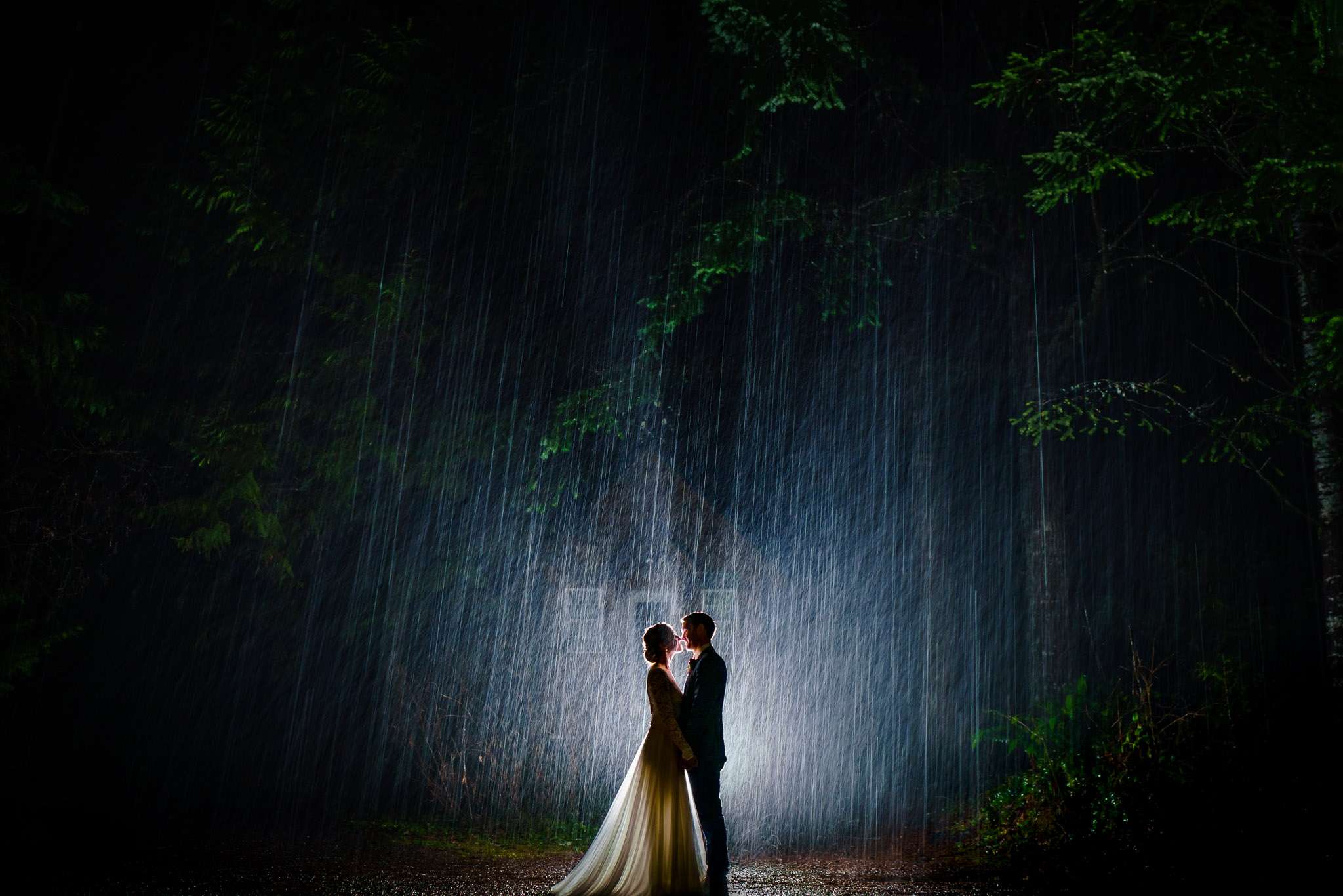 Silhouette of a bride and groom kissing in the rain