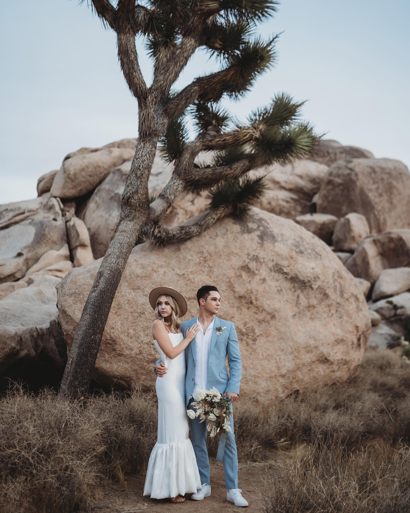 A bride and groom posing in a desert