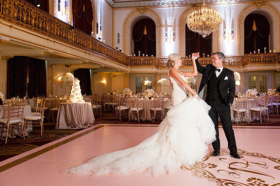 A wedding reception hall image by Leeann Marie of the bride and groom in the middle of a twirl on the dance floor.