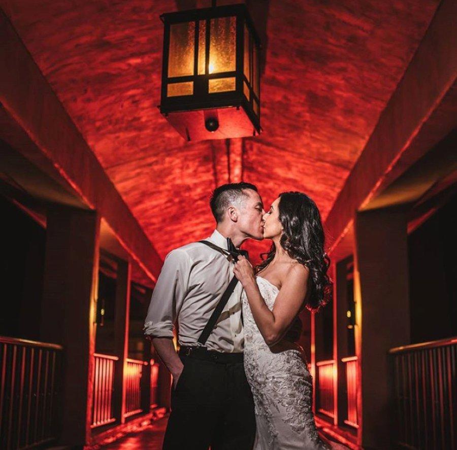 Bride and groom kissing in front of a red-lit background