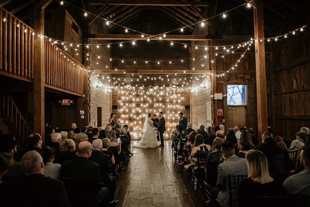 a wedding ceremony in a barn where the bride and groom are taking their vows surrounded by the guests